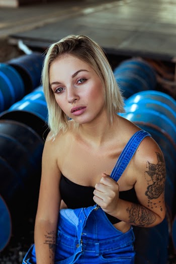 Woman In Black Bandeau And Blue Denim Overalls Sitting On Barrels
