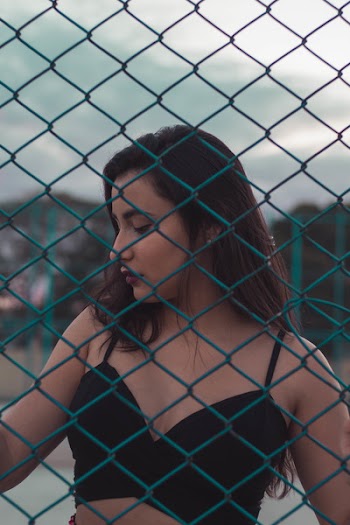 Woman in Black Bra Near Blue Grid Fence