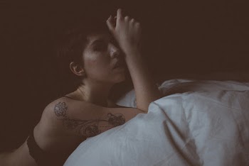 Woman in Black Brassiere Lying on Bed With White Linen