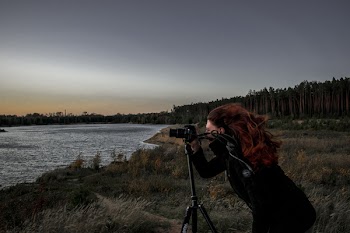 Woman in Black Coat Holding Dslr Camera With Stand Near Body of Water