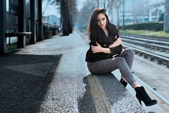 Woman in Black Coat Sitting Near the Train Track
