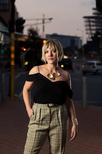 Woman in Black Cold-shoulder Top and Grey Plaid Pants With Her Hands in Her Pocket