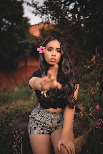 Woman In Black Crew Neck T-shirt And Grey Plaid Shorts Standing Near Bushes In Garden