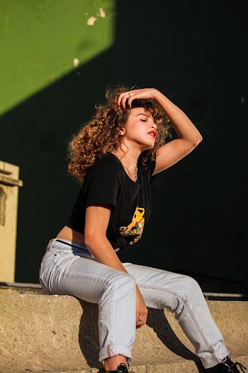 Woman in black crew-neck t-shirt sitting on stairs with her hand on her hair