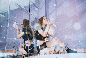 Woman in Black Crop Top Sitting Indoors While Playing Bubbles