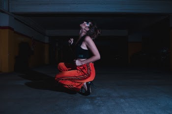 Woman in Black Crop Top Sitting on Concrete Floor