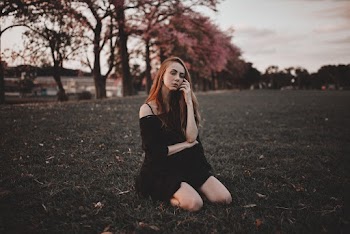 Woman in Black Dress Kneeling on Grass