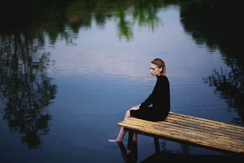 Woman In Black Dress Sitting on Brown Dock