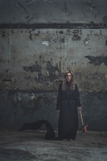woman in black dress standing in front of gray wall