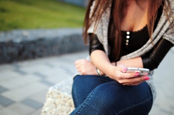 Woman in Black Elbow Sleeve Shirt and Blue Denim Jeans Sitting on the Grey Rock during Daytime