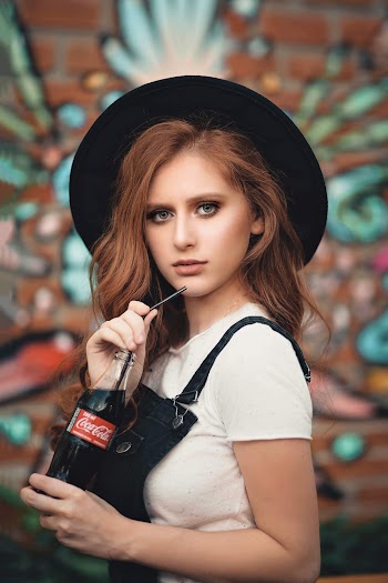 Woman in Black Hat and White Shirt Holding Coca-cola Bottle