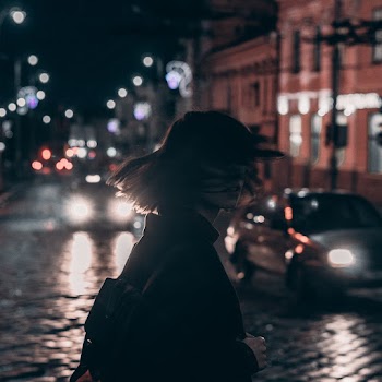 Woman in Black Jacket Carrying Backpack With Tousled Hair Walking On The Street At Night