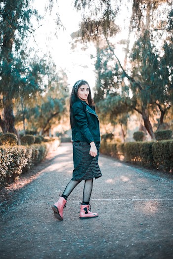 Woman in Black Jacket, Skirt, and Pink Boots