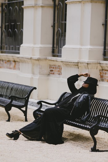 Woman in Black Leather Jacket Sitting Black Metal Bench