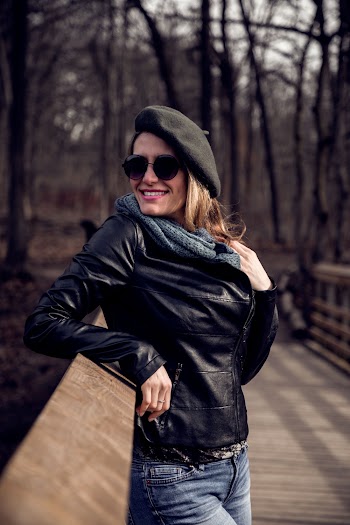 Woman in Black Leather Jacket Standing on Brown Wooden Bridge While Smiling