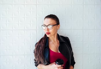 Woman in Black Leather Jacket Wearing Eyeglasses Holding Coffee Cup