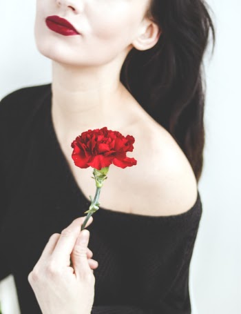 Woman in Black One-shoulder Top Holding Red Carnation