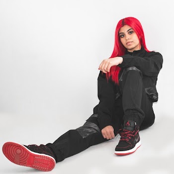 Woman in Black Overalls and Red Hair Sitting Down