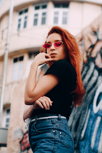 Woman in Black Shirt and Blue Denim Bottoms Holding Her Chin