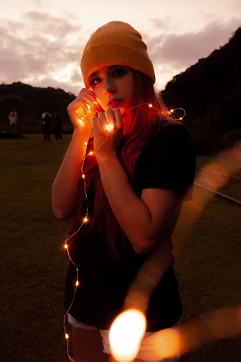 Woman in Black Shirt and White Shorts Holding Lighted String Light
