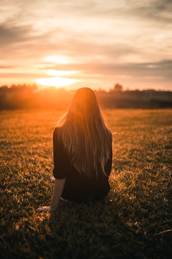 Woman in Black Shirt Sitting on Grass during Sunset