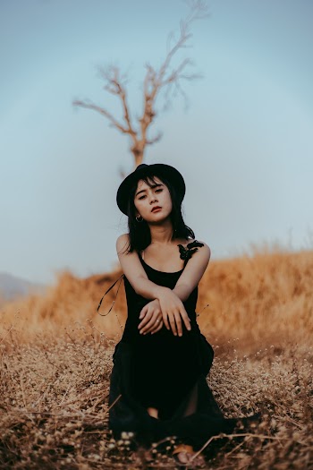 Woman in Black Sleeveless Dress Sitting Outdoors