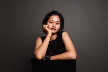 Woman in Black Sleeveless Top Leaning on Black Table While Holding Cheek