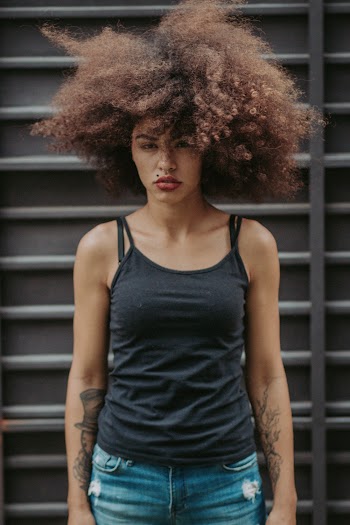 Woman in Black Spaghetti Top and Jeans With Big Curly Hair