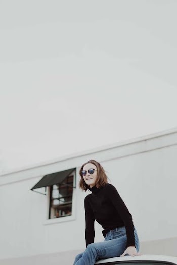 woman in black sweatshirt in front of white building