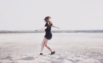Woman In Black T-shirt And Black Denim Shorts Walking On Sand