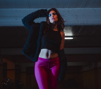 Woman in Black Tank Top and Black Jacket Standing While Right Hand Near Head
