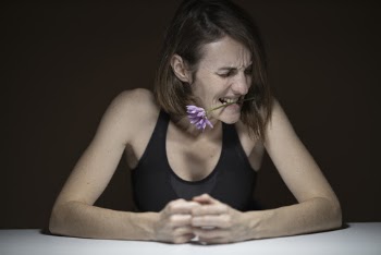 Woman in Black Tank Top Biting Purple Petaled Flower