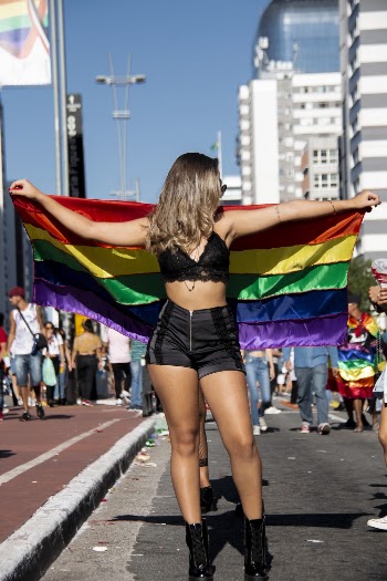 Woman In Black Top And Shorts Holding Rainbow Flag