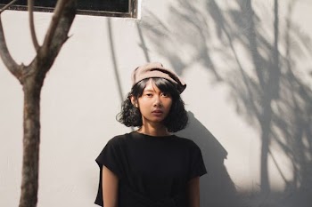 woman in black top behind white wall