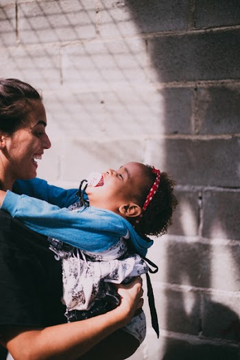 Woman in Black Top Carrying Girl Wearing Blue Hoodie