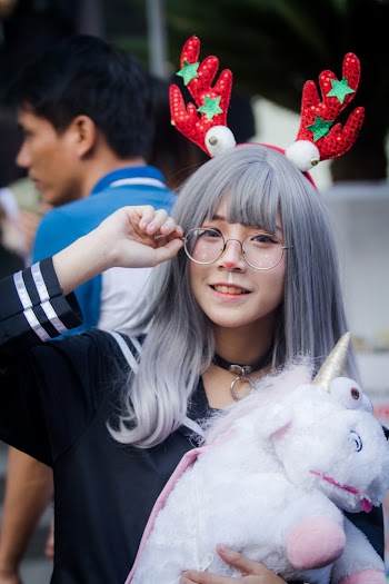 Woman in Black Top Holding White Unicorn Plush Toy