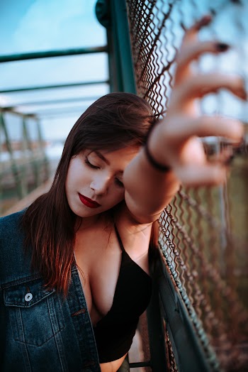 Woman In Black Top Leaning On Chain Link Fence