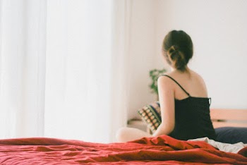 Woman in Black Top Sitting on Bed Inside Room