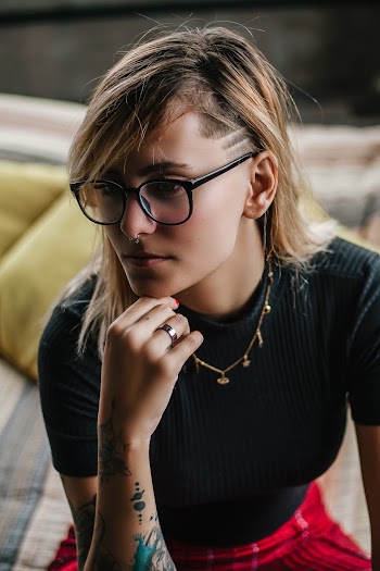 Woman in Black Top With Her Chin on Her Right Wrist While Sitting on Bed