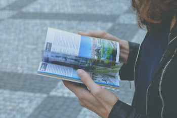 Woman in Black Zipped Jacket Hoding White and Blue Book