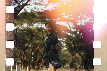 Woman in Blue and Red Floral Dress Standing Under Green Tree
