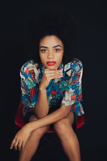 Woman in Blue and Red T-shirt Sitting on Chair