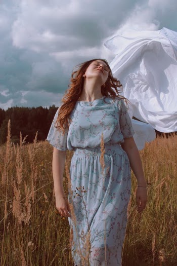Woman in Blue and White Floral Dress Standing on Brown Grass Field · Free Stock Photo