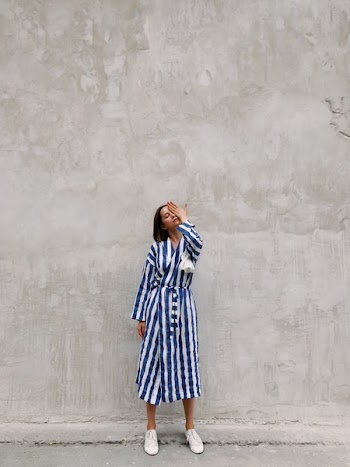 Woman in Blue and White Striped Dress Covering Her Left Eye