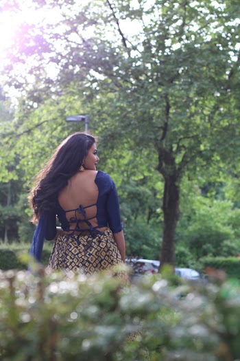 Woman in Blue Backless Shirt and Brown Argyle Pattern Bottoms Standing Near Tree