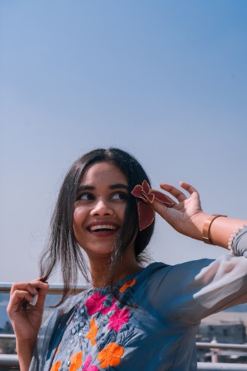 Woman in Blue Blouse Holding Flower by Her Ears Smiling