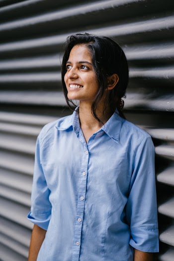 Woman in Blue Button-up Shirt Leaning on Roller Shutter