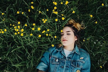 woman in blue chambray jacket lying on green grass