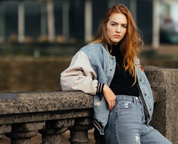 Woman in Blue Denim Bottoms Leans on Grey Concrete Balustrades