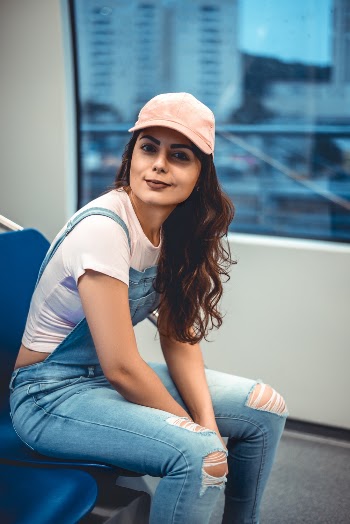 Woman in Blue Denim Dungarees and White Shirt Sits on Blue Chair